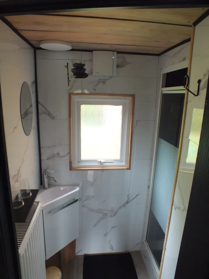 La salle d’eau avec sa douche et son habillage en bois