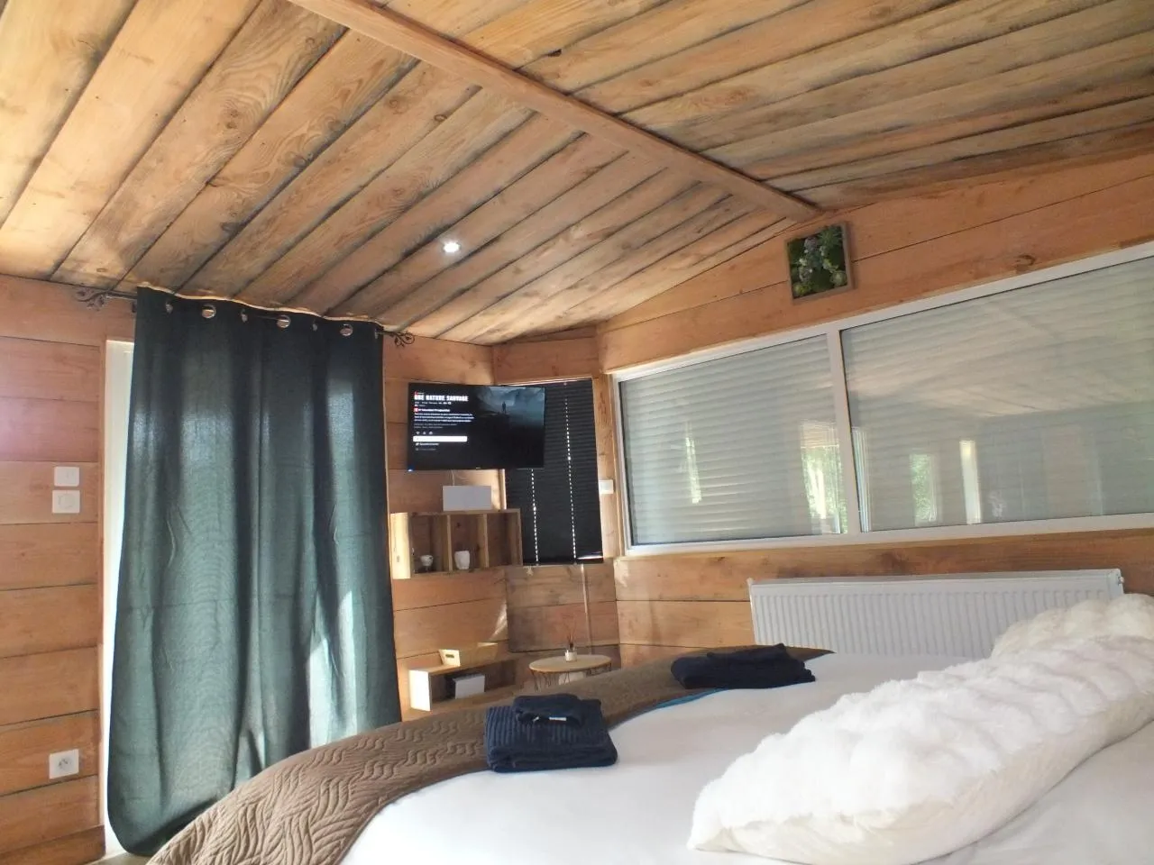 La chambre principale avec son grand lit, sa télévision et ses parois en bois